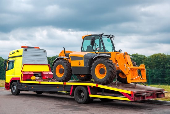Flatbed tow truck transporting a yellow bulldozer